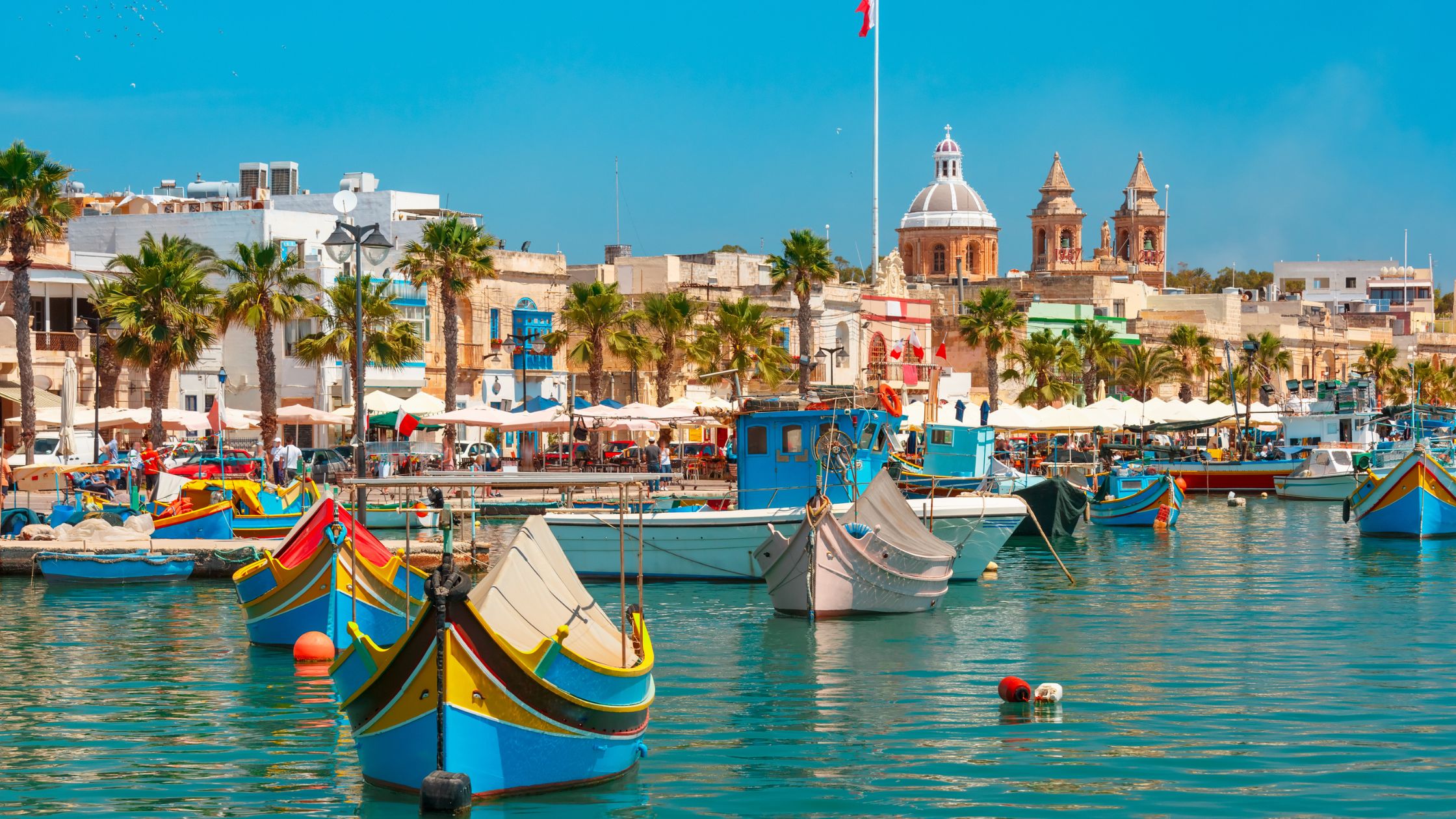 Image shows boats at Marsaxlokk Market, in Malta.